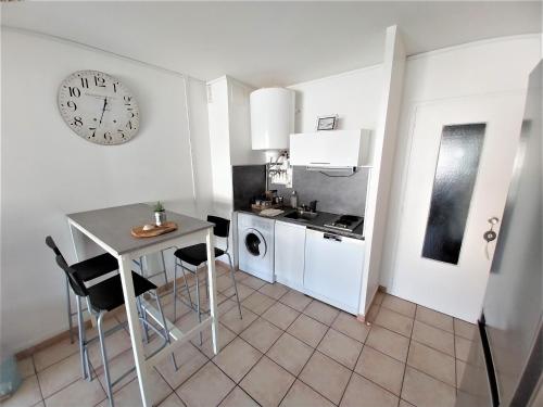 une cuisine avec une table et une horloge au mur dans l'établissement Studio les pieds dans l'eau au Cap d'Agde, au Cap d'Agde