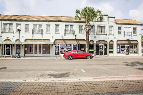 a red car parked in front of a building at OYO Historic Cameron Hotel Brownsville I-69E in Brownsville
