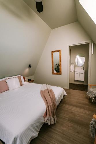 a bedroom with a large white bed and a mirror at The Cove Tasmania in Devonport
