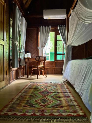 a bedroom with a bed and a table and a rug at Beehive Cottages in Amed