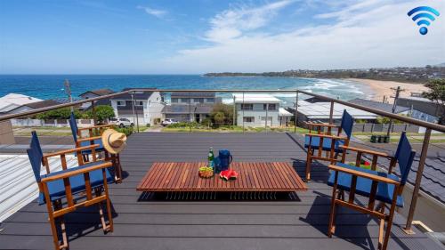 a table and chairs on a deck with a view of the ocean at Beachcomber in Kiama Downs