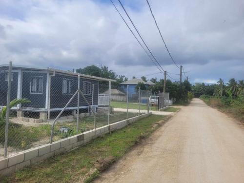 a dirt road with a house and a fence at Avondale Place in Nuku‘alofa