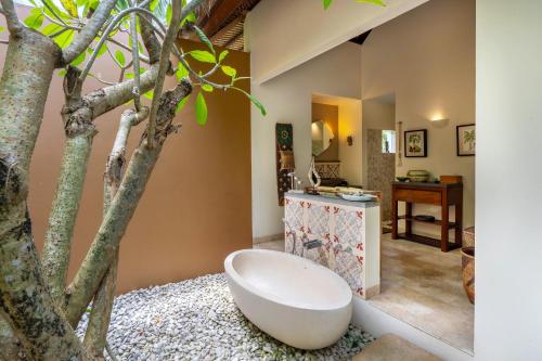 a bathroom with a bath tub next to a tree at Villa Palem in Tabanan