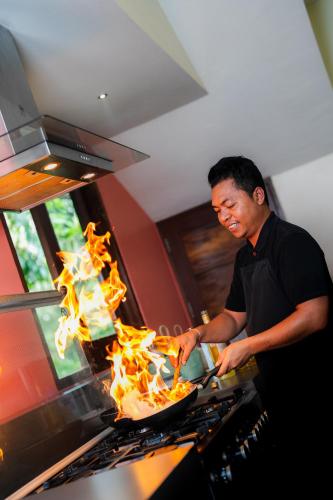 a man cooking food on a stove with flames at Villa Palem in Tabanan