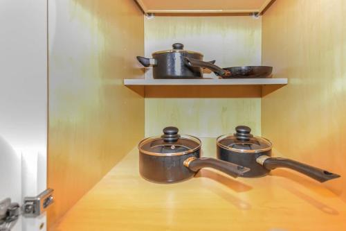 three pots and pans on a shelf in a kitchen at Stylish One-Bedroom Unit with Easy Ground Access in Reno
