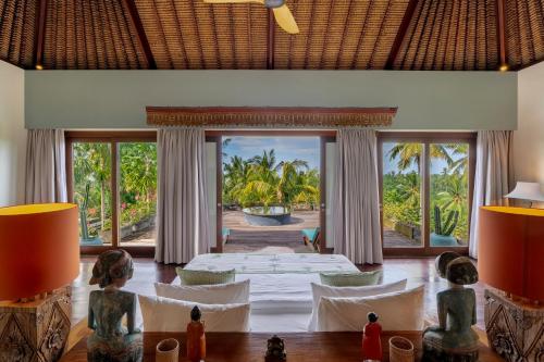 a room with a bed and a view of the ocean at Villa Palem in Tabanan