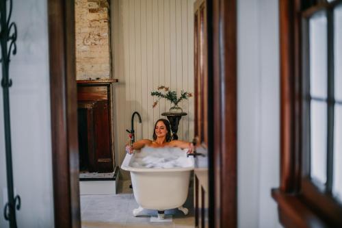 a woman taking a bath in a bath tub at Littlebourne Guest House in Bathurst