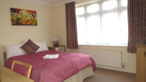 a bedroom with a large bed with a pink blanket at Montrose Guest House in Romford
