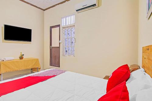 a bedroom with a bed and a tv on the wall at Hotel O New Bunga Sonsang Homestay Syariah in Padang