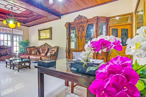 a living room with a table and purple flowers at Hotel O New Bunga Sonsang Homestay Syariah in Padang