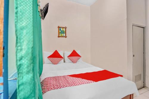 a bedroom with a bed with red and white pillows at OYO Life 90523 Homestay Jenggolo in Sidoarjo