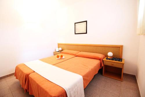 een slaapkamer met een bed met oranje lakens en een tafel bij Mariposa 1024 IBERPLAYA in Salou