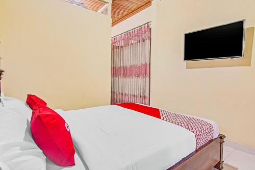 a bedroom with a bed with red pillows and a tv at Hotel O New Bunga Sonsang Homestay Syariah in Padang