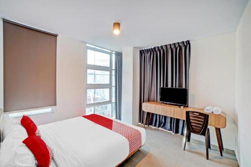 a bedroom with a bed and a desk with a computer at Hotel O Gamacity Residence in Pulauberayan Dadap