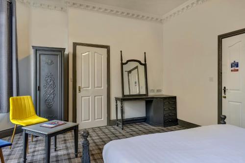 a bedroom with a bed and a yellow chair at Empire Hotel in Leicester
