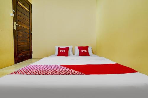 a bed with two red pillows in a room at Hotel O Wisma Al-fahmi Syariah in Maniskaler