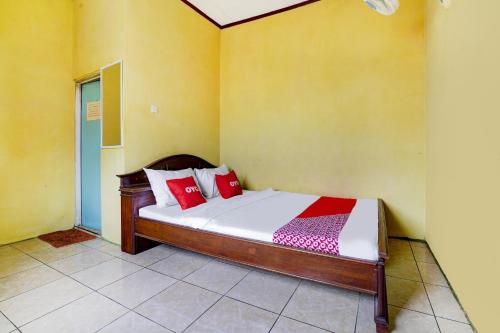 a bedroom with a bed with red and white pillows at Hotel O Wisma Al-fahmi Syariah in Maniskaler