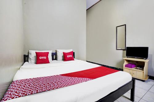 a bedroom with a bed with red pillows and a tv at Hotel O Wisma Al-fahmi Syariah in Maniskaler
