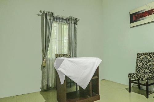 a room with a table and a chair and a curtain at Hotel O Papi Inn Guesthouse in Palangkaraya