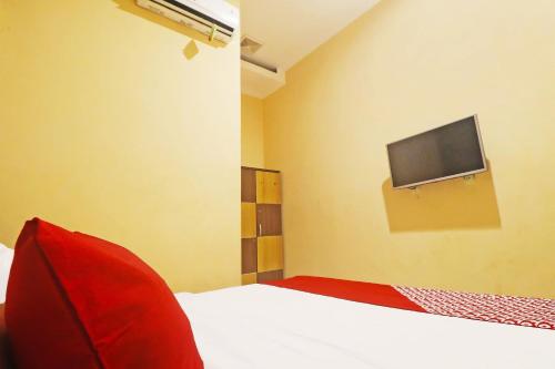 a bedroom with a bed with a tv on the wall at Hotel O Papi Inn Guesthouse in Palangkaraya