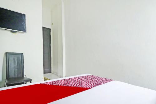 una camera con letto rosso e sedia nera di Hotel O Papi Inn Guesthouse a Palangkaraya