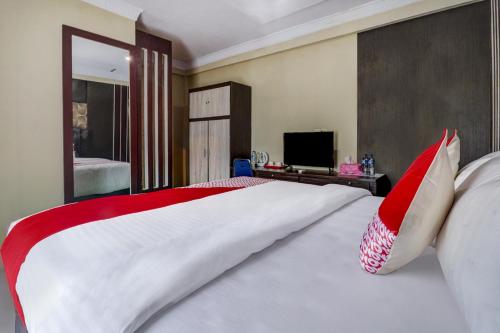 a bedroom with a large bed with red and white pillows at Collection O 90564 Hotel Merangin Syariah in Bangko