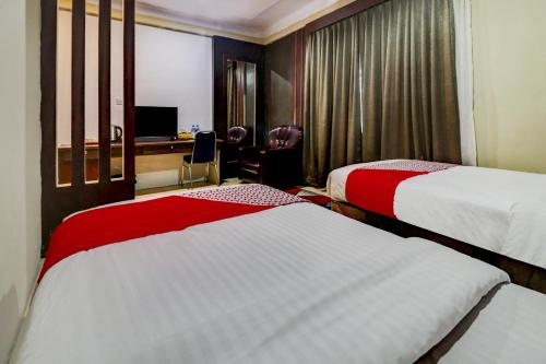 a hotel room with two beds and a desk at Collection O 90564 Hotel Merangin Syariah in Bangko