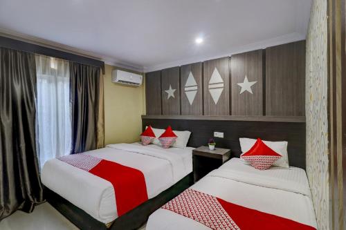 a bedroom with two beds with red and white sheets at Collection O 90564 Hotel Merangin Syariah in Bangko