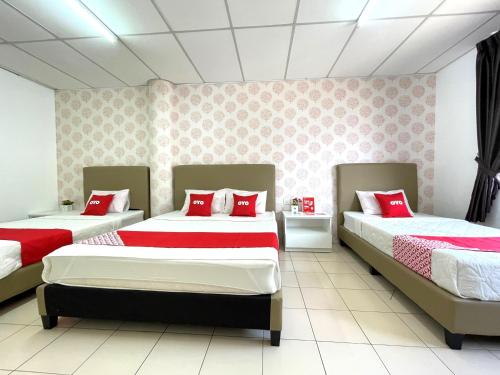 a bedroom with three beds with red pillows on them at Hotel O Wg Guest House in George Town