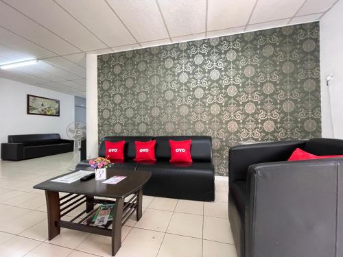a living room with two black couches and red pillows at Hotel O Wg Guest House in George Town
