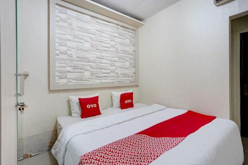 a white bedroom with red pillows on a bed at OYO Life 90606 Glass House Citraland Syariah in Surabaya