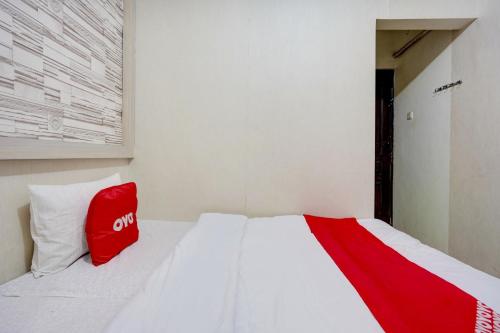 a white bed with a red bag sitting on it at OYO Life 90606 Glass House Citraland Syariah in Surabaya