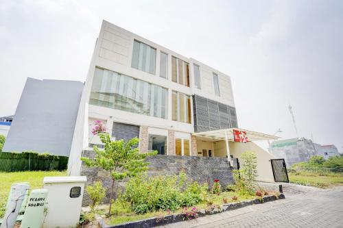 a large white building with windows on a street at OYO Life 90606 Glass House Citraland Syariah in Surabaya