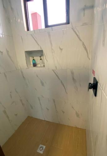 a bathroom with white marble walls and a window at The Lookout Hideaway in Baños