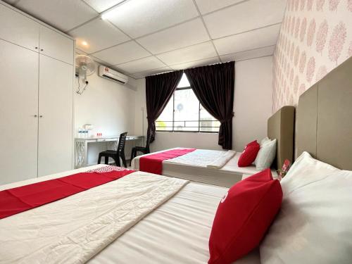 two beds in a room with red pillows at Hotel O Wg Guest House in George Town
