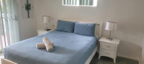 a bed with a stuffed animal sitting on top of it at Cabbage Palm Holiday Home in Agnes Water