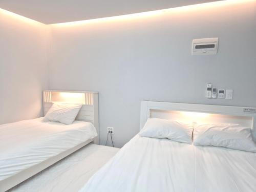 two beds in a room with white walls at Liverpool & Spa in Jeju