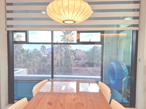 a dining room with a table and a large window at Liverpool & Spa in Jeju