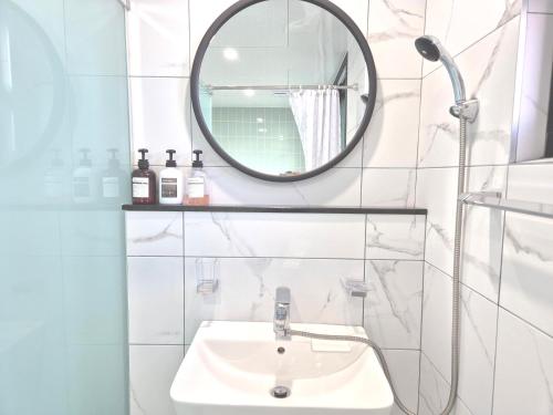 a white bathroom with a sink and a mirror at Liverpool & Spa in Jeju