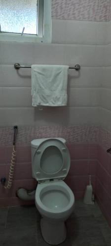 a bathroom with a white toilet and a window at The Coffee Residences at KINGS MILLENNIUM APARTMENTS, near JKI Airport 3 Bedroom in Nairobi