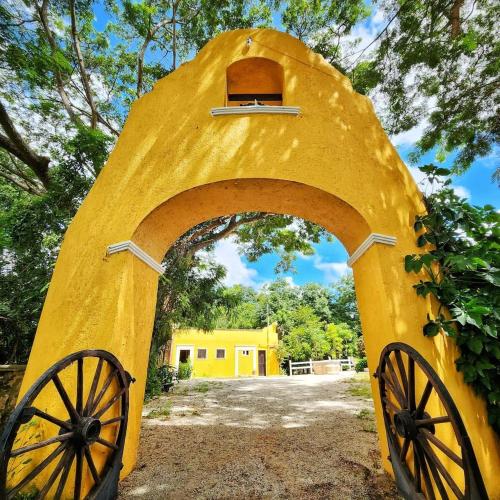 a yellow arch with a wooden structure withoked wheels at Hacienda San Antonio in Kanasín