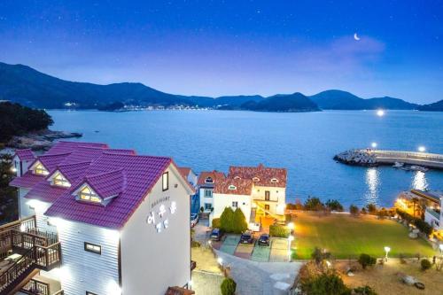 a building with a purple roof next to a body of water at Geojedo Harmony Spa & Pet Pension in Geoje 