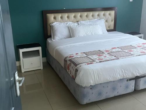 a bedroom with a bed and a night stand next to it at The Coffee Residences at KINGS MILLENNIUM APARTMENTS, near JKI Airport 3 Bedroom in Nairobi