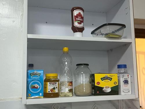 a refrigerator shelf with food and other items on it at The Coffee Residences at KINGS MILLENNIUM APARTMENTS, near JKI Airport 3 Bedroom in Nairobi