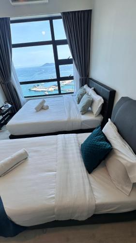two beds in a hotel room with a large window at JQ1 SEA & POOL or CITY View WIFI I WASHING MACHINE for Some Units I CUCKOO WATER Jesselton Quay by R2 in Kota Kinabalu