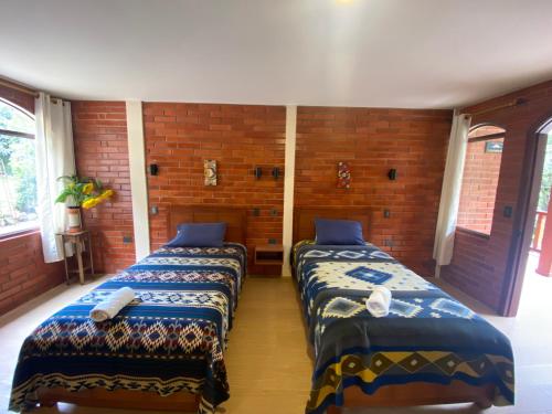 two beds are in a room with a brick wall at The Lookout Hideaway in Baños