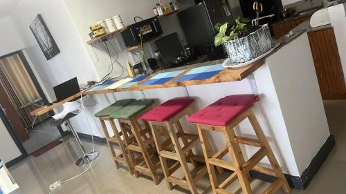 a kitchen with three stools at a counter at The Coffee Residences at KINGS MILLENNIUM APARTMENTS, near JKI Airport 3 Bedroom in Nairobi