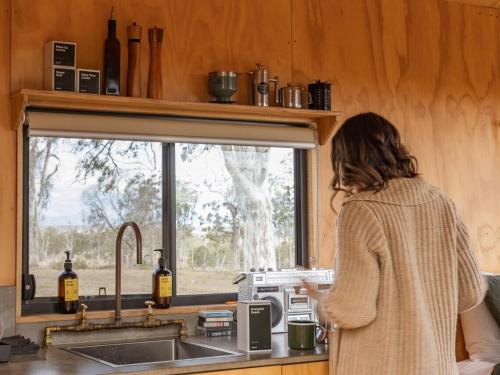 Una mujer parada en una cocina mirando por una ventana. en Pet Friendly Cabin Surrounded by Wilderness - Gili, en Coleyville