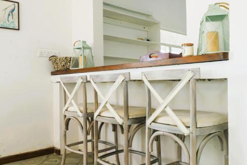 a bar with three stools at a kitchen counter at Magnolia House Mirissa in Mirissa
