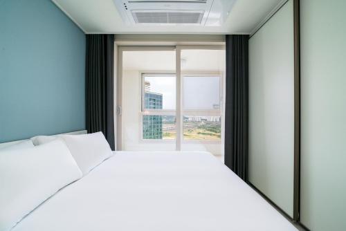 a bedroom with a white bed and a window at Urbanstay Songdo Moonlight Park in Incheon